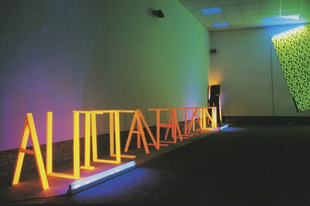 Autocanibalización Emulsion naranja fluorescente y luz negra Letras en madera 50 x 70 cm 2002 Museo Gustavo de Maeztu, 2002